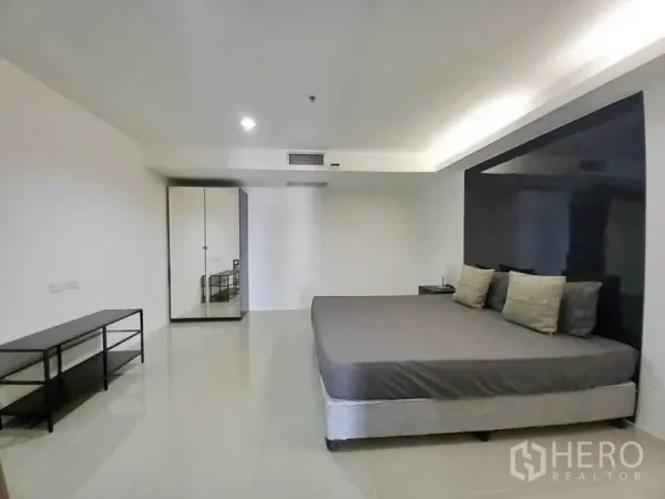 Condominium for rent in Khlong Toei, Bangkok - Wide bedroom view showing bed, feature wall, wardrobe and tiled floor.