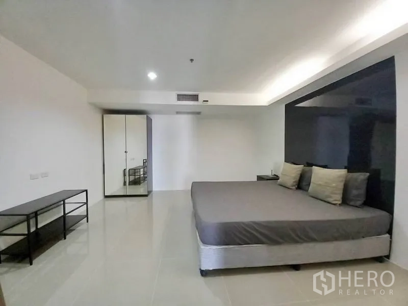 Condominium for rent in Khlong Toei, Bangkok - Wide bedroom view showing bed, feature wall, wardrobe and tiled floor.