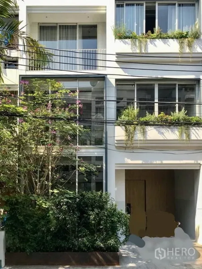联排别墅 出租在Khlong Toei, Bangkok - 现代白色三层联排外立面，大面积落地窗与绿植花槽。