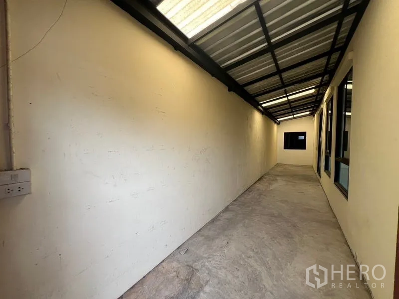 Townhouse for rent or sale in Khlong Toei, Bangkok - Long covered side passage with metal roofing and windows.