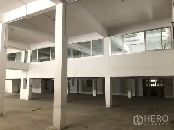 Factory for rent in Prawet, Bangkok - Spacious factory floor with high ceilings and mezzanine offices with glass windows.