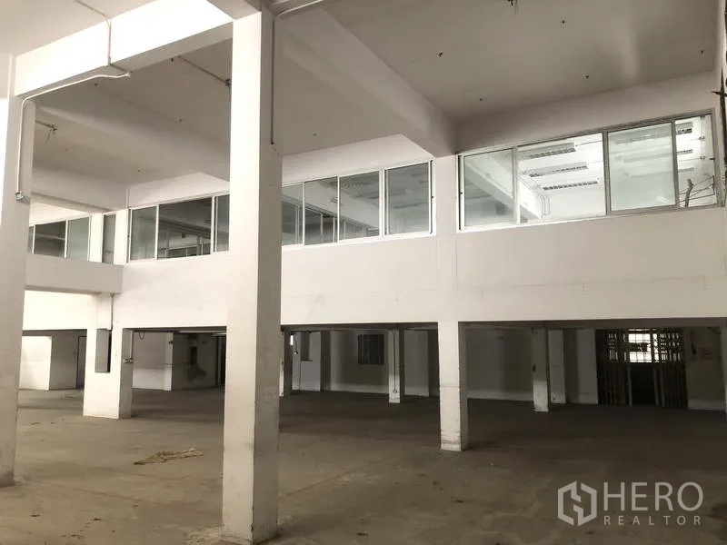 Factory for rent in Prawet, Bangkok - Spacious factory floor with high ceilings and mezzanine offices with glass windows.