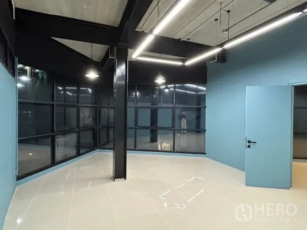 Office Space for rent in Chatuchak, Bangkok - Industrial-style office corner with panoramic glazing, exposed beams and sleek pendant lighting over polished tiles.
