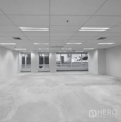 Office Space for rent - Open office area with columns, grid ceiling lighting and windows facing skyline.
