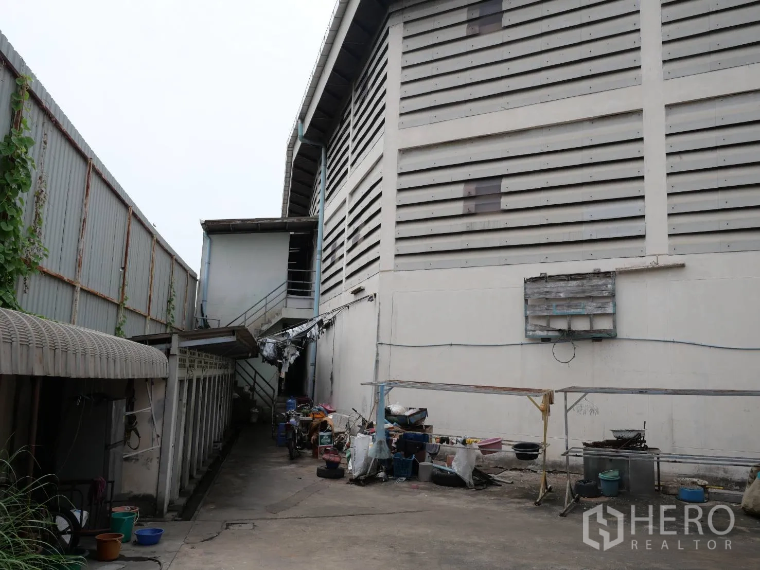 Factory for rent or sale in Bang Khun Thian, Bangkok - Rear service lane beside the factory wall with external stairs and worker rooms.