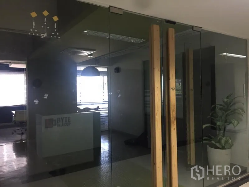 办公空间 出租在Bang Kapi, Bangkok - 玻璃隔断后的接待区，配大窗采光、吊顶照明与室内绿植的现代办公室。