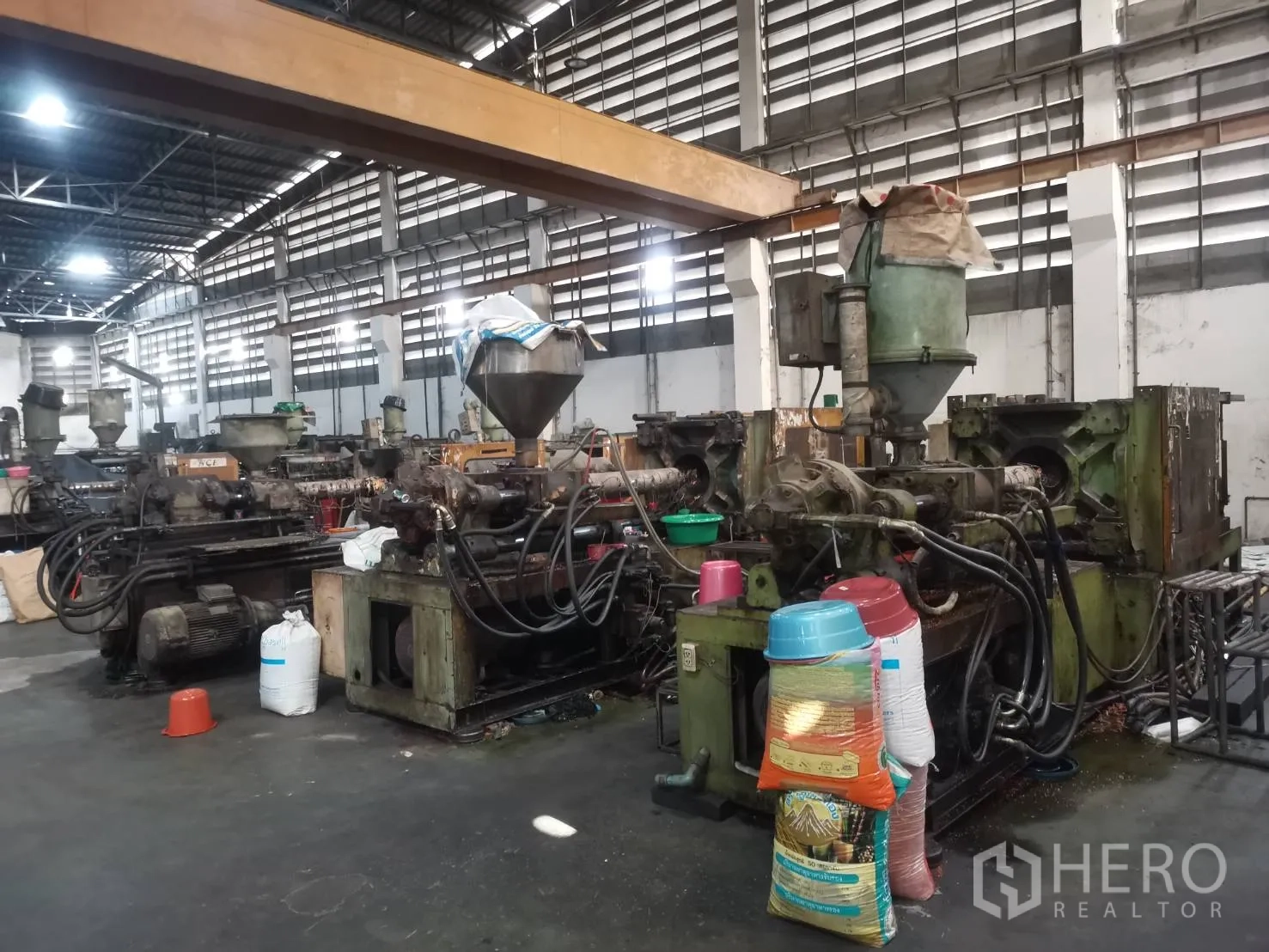 Factory for rent or sale in Bang Khun Thian, Bangkok - Row of plastic injection molding machines beneath an overhead crane beam.
