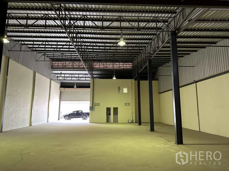 Factory for sale in Mueang Samut Prakan, Samut Prakan - High-ceiling warehouse showing lighting, steel beams and clear floor space.