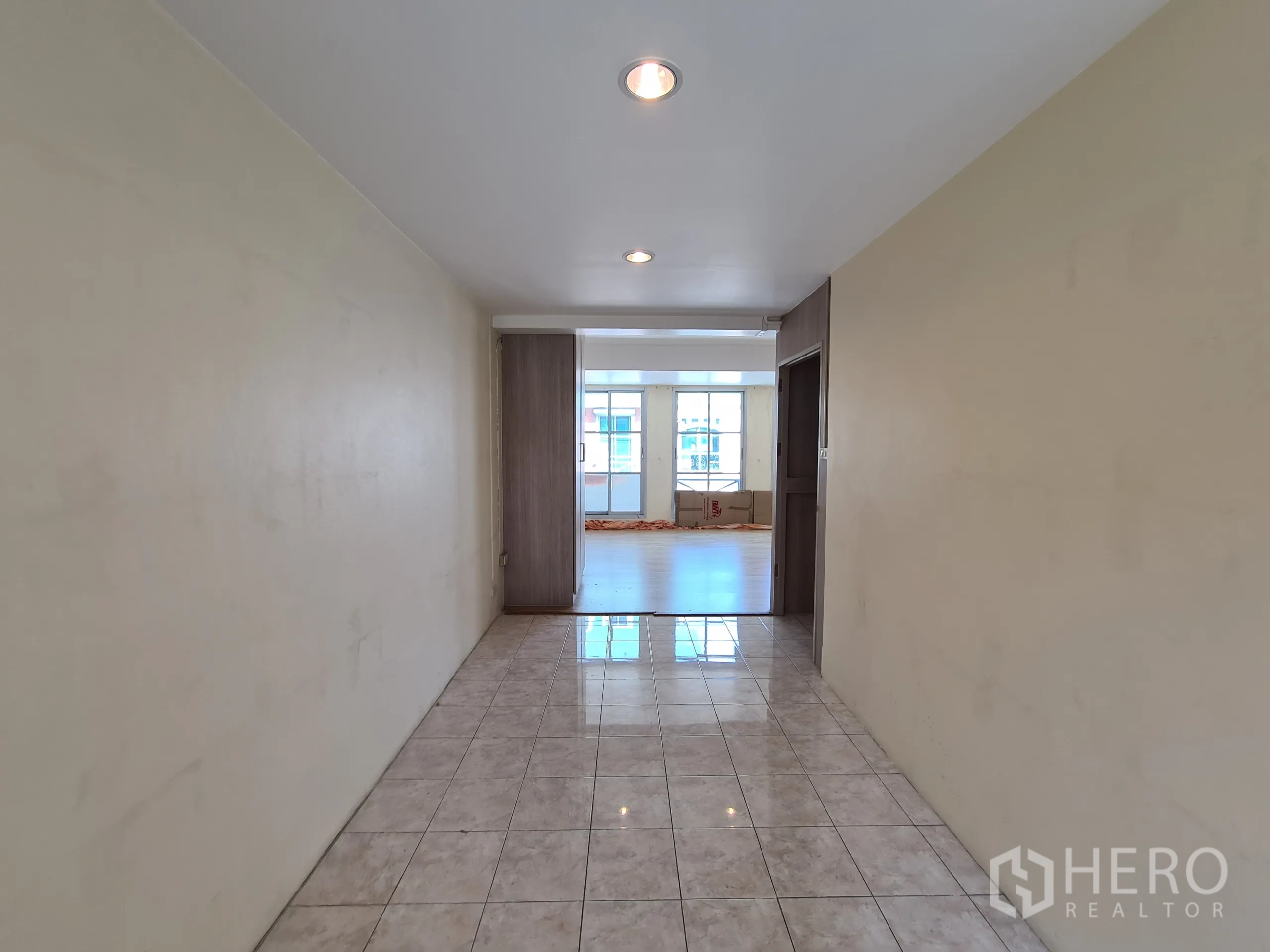 Shophouse for rent or sale in Sathon, Bangkok - Long corridor opening to a sunlit office-style room with full-height windows.