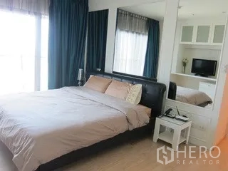 Condominium for rent in Khlong Toei, Bangkok - Master bedroom with large bed, floor-to-ceiling window and bedside table.