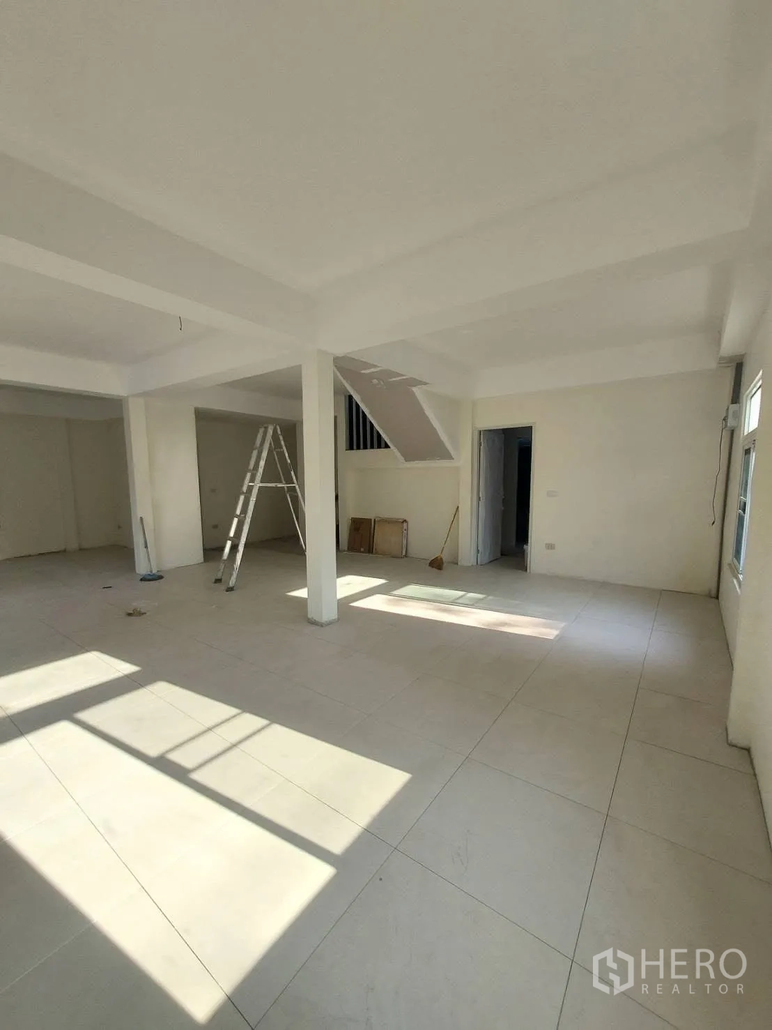Detached House for rent in Watthana, Bangkok - Sunlit living area with large-format tiles and an under-stair area.