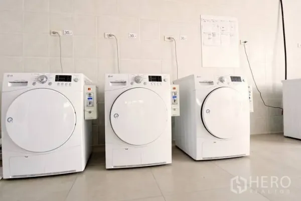 Condominium for rent in Khlong Toei, Bangkok - Shared laundry room featuring three front-loading washing machines.