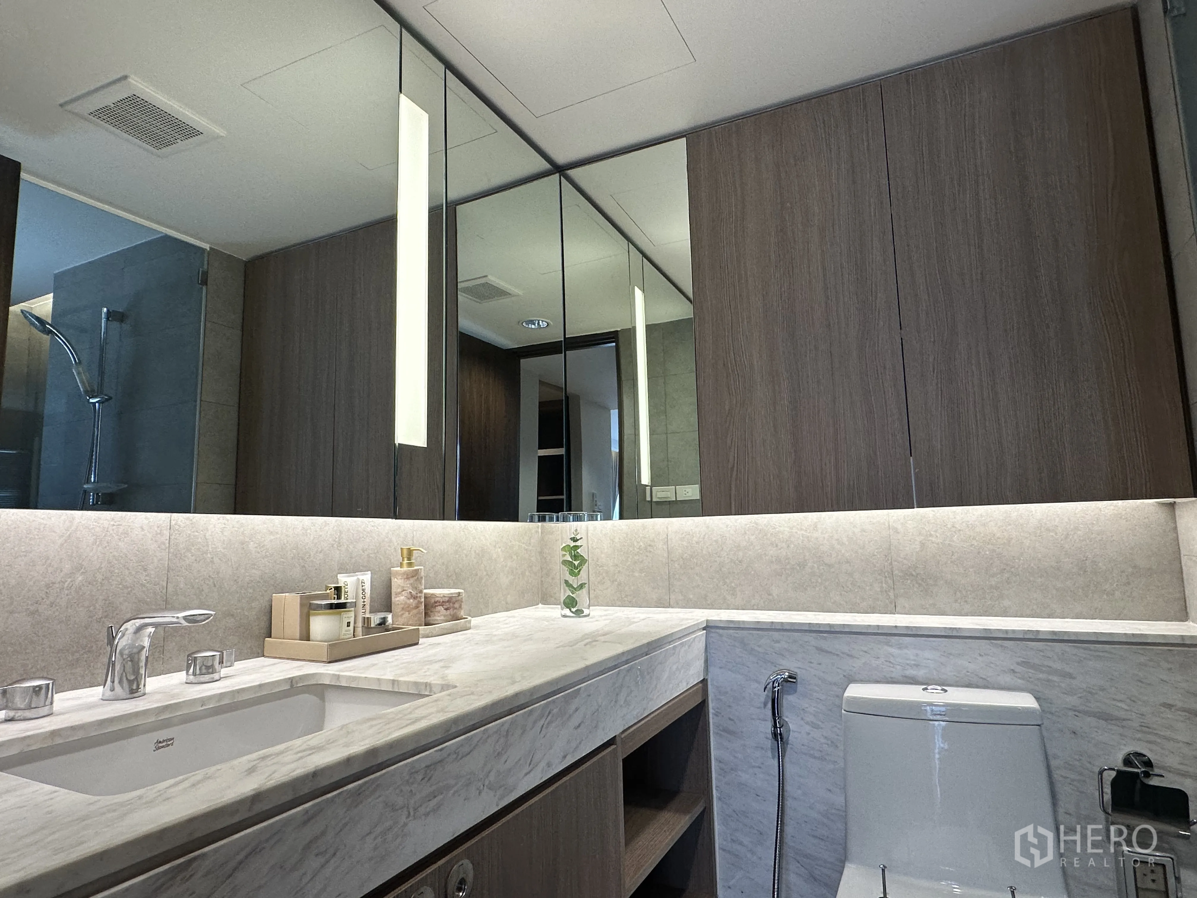 Condominium for rent in Khlong Toei, Bangkok - Second bathroom with large illuminated mirror and marble vanity.