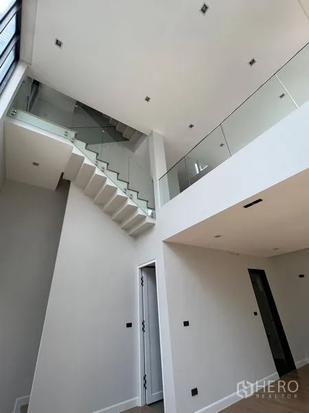 Home Office for sale in Wang Thonglang, Bangkok - Atrium-style living area with soaring ceilings and a sleek white staircase with glass railings.