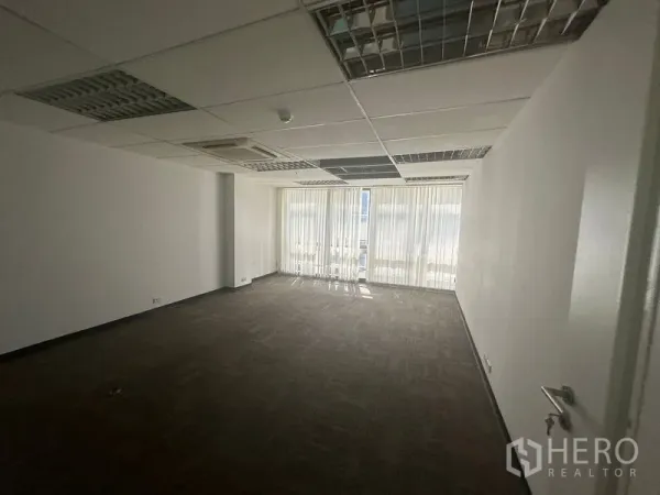 Office Space for rent in Khlong Toei, Bangkok - Large rectangular office with carpet tiles, cassette air‑con and full‑height windows with blinds.