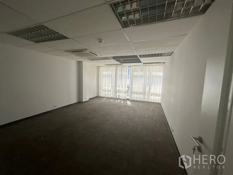 Office Space for rent in Khlong Toei, Bangkok - Large rectangular office with carpet tiles, cassette air‑con and full‑height windows with blinds.