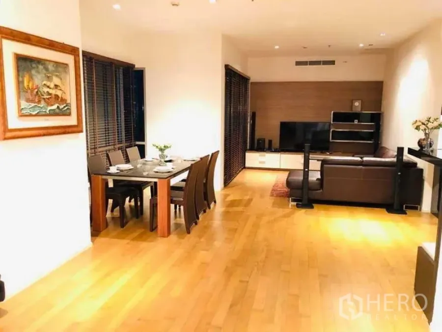Condominium for rent or sale in Watthana, Bangkok - Spacious lounge and dining room with TV wall, hardwood floors and ambient lighting.