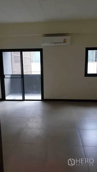 Townhouse for rent or sale in Khlong Toei, Bangkok - Bright bedroom with sliding glass door to balcony and wall-mounted air conditioner.