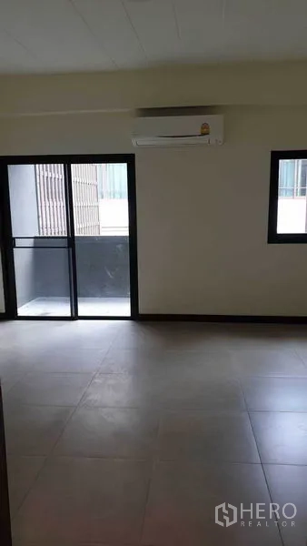 Townhouse for rent or sale in Khlong Toei, Bangkok - Bright bedroom with sliding glass door to balcony and wall-mounted air conditioner.