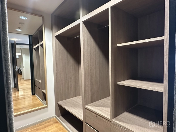 Condominium for rent in Khlong Toei, Bangkok - Walk-in closet with custom wood cabinetry and full-height mirror.