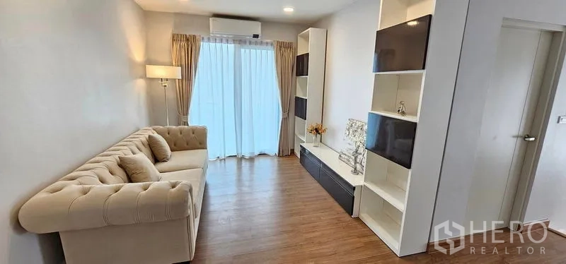 Detached House for rent in Bang Phli, Samut Prakan - Cozy family room with tufted sofa, built-in media shelves and sliding doors to the balcony.