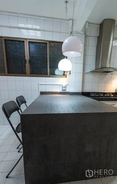 Townhouse for rent in Watthana, Bangkok - Kitchen island with pendant lights and two bar stools.