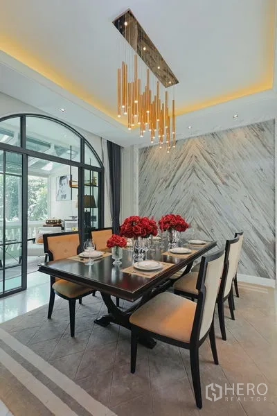 Detached House for rent or sale in Watthana, Bangkok - Formal dining room with statement chandelier and marble feature wall.