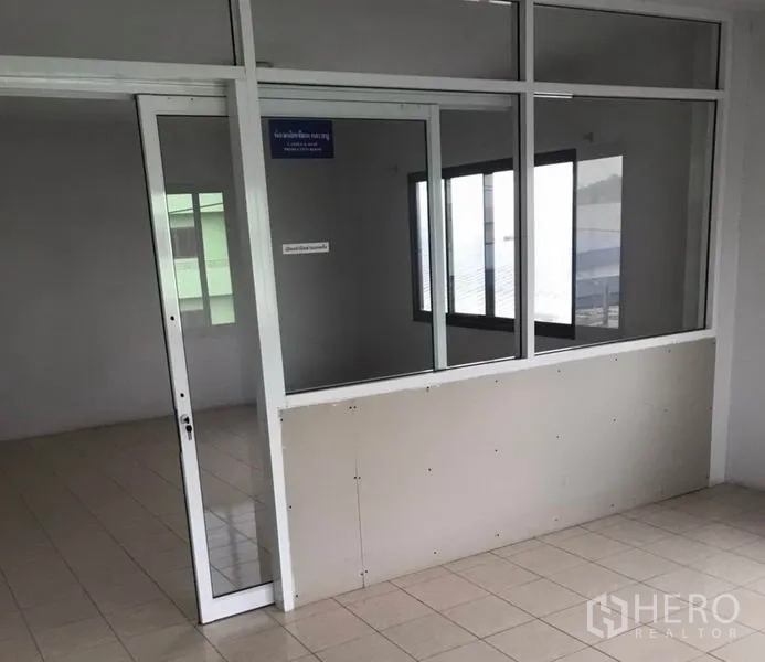 Factory for rent in Bang Bua Thong, Nonthaburi - Glass-walled office room with sliding door and tiled floor.