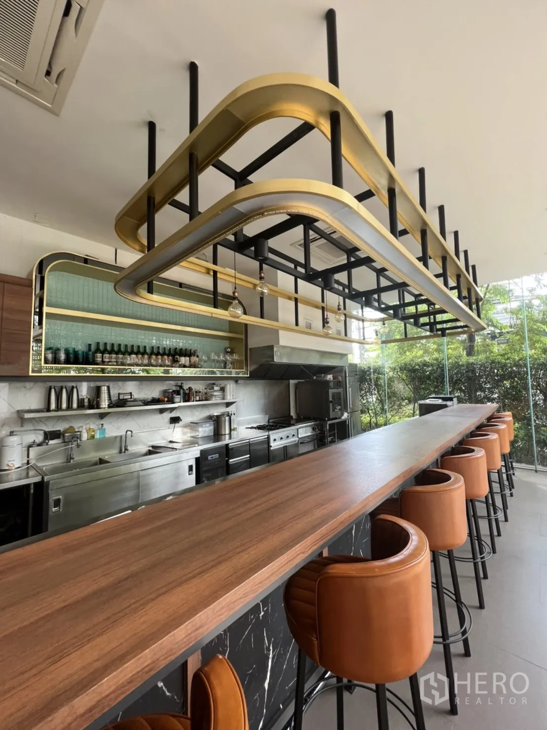 Retail Space for rent in Watthana, Bangkok - Close view of bar-height counter and gold-black ceiling rack with seating and marble-clad base.