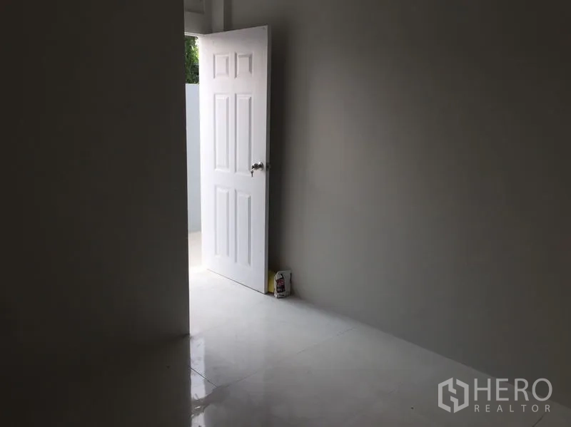 Warehouse for sale in Khlong Luang, Pathum Thani - Interior view of a white door opening to a small outdoor area on tiled floor.