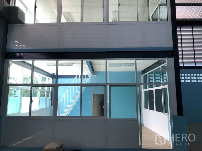 Factory for rent or sale in Bang Bua Thong, Nonthaburi - Two-storey internal office with stair access and large windows inside the hall.