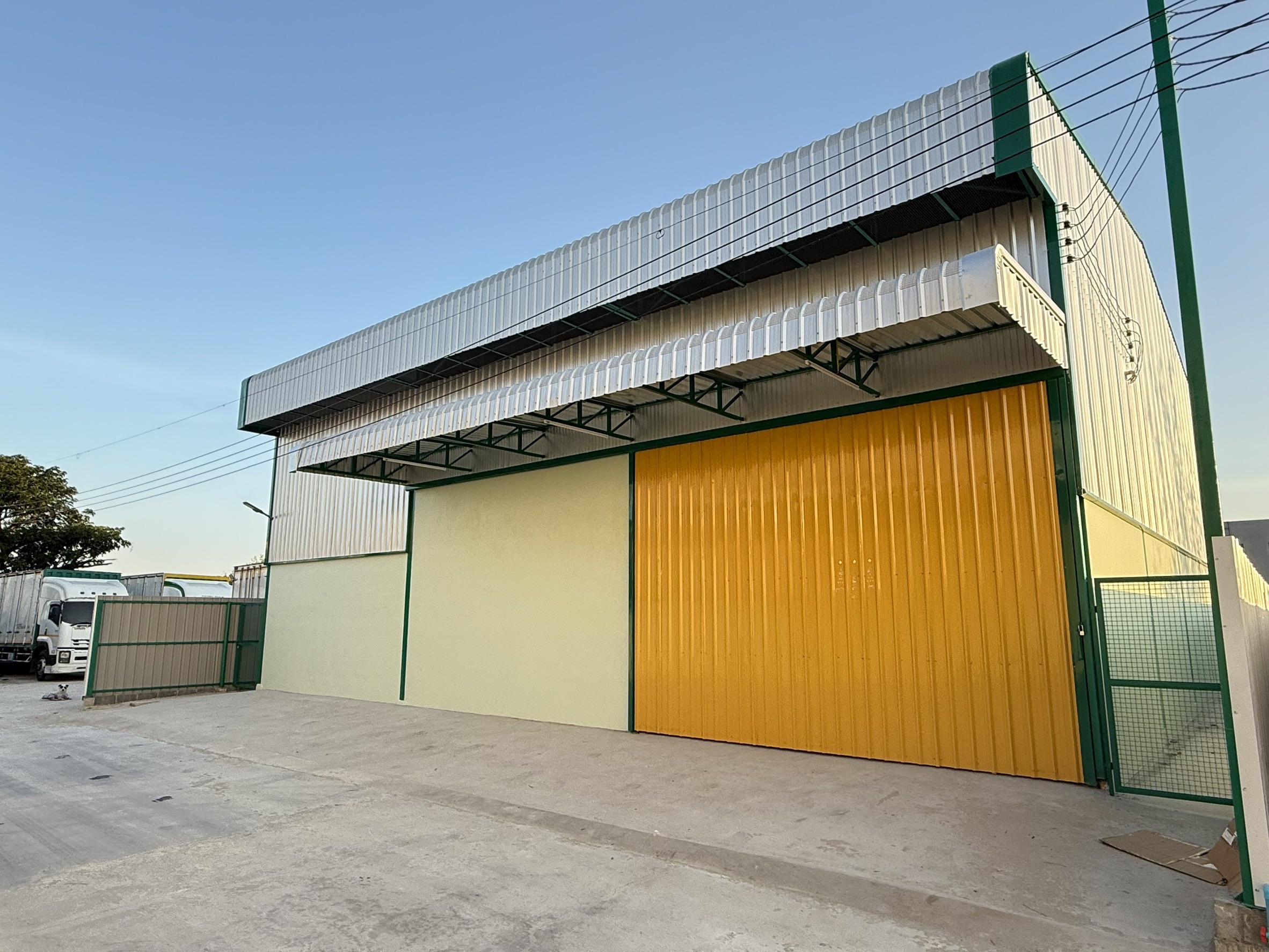 Warehouse for rent in Lat Krabang, Bangkok - Modern warehouse exterior with large yellow sliding door, canopy, and concrete loading apron in Lat Krabang.