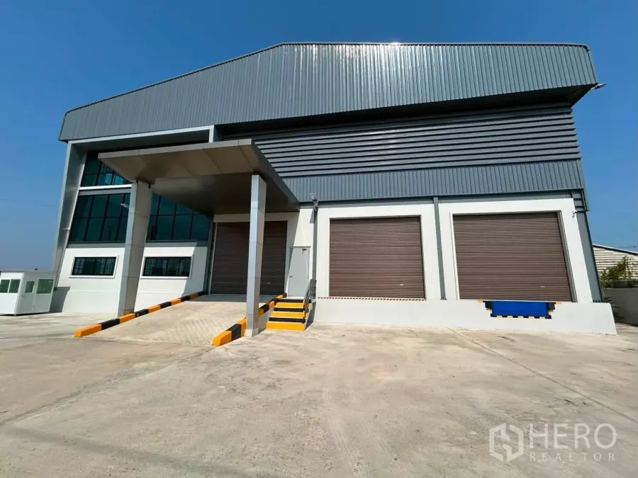 仓库 for rent in Bang Phli, Samut Prakan - 仓库外立面，带遮雨装卸区、坡道和三扇卷帘装卸门。