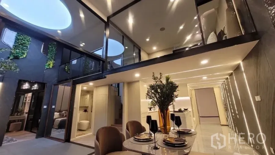 Detached House for sale in Watthana, Bangkok - Open-plan dining beneath a mezzanine with skylights and a green feature wall in the atrium.