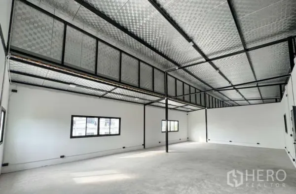 Warehouse for rent in Bang Phli, Samut Prakan - Open‑plan mezzanine office space with windows, insulated roof panels and black steel framing.