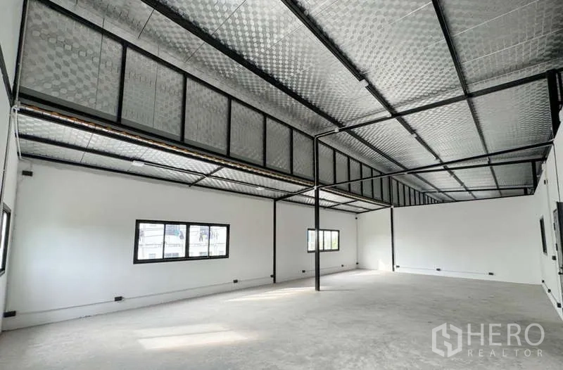 Warehouse for rent in Bang Phli, Samut Prakan - Open‑plan mezzanine office space with windows, insulated roof panels and black steel framing.