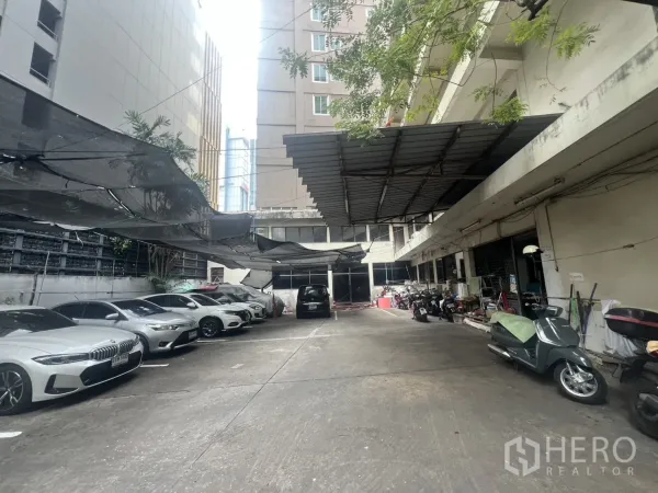 Shophouse for rent - Shaded on-site car park accommodating multiple cars and motorbikes between buildings.