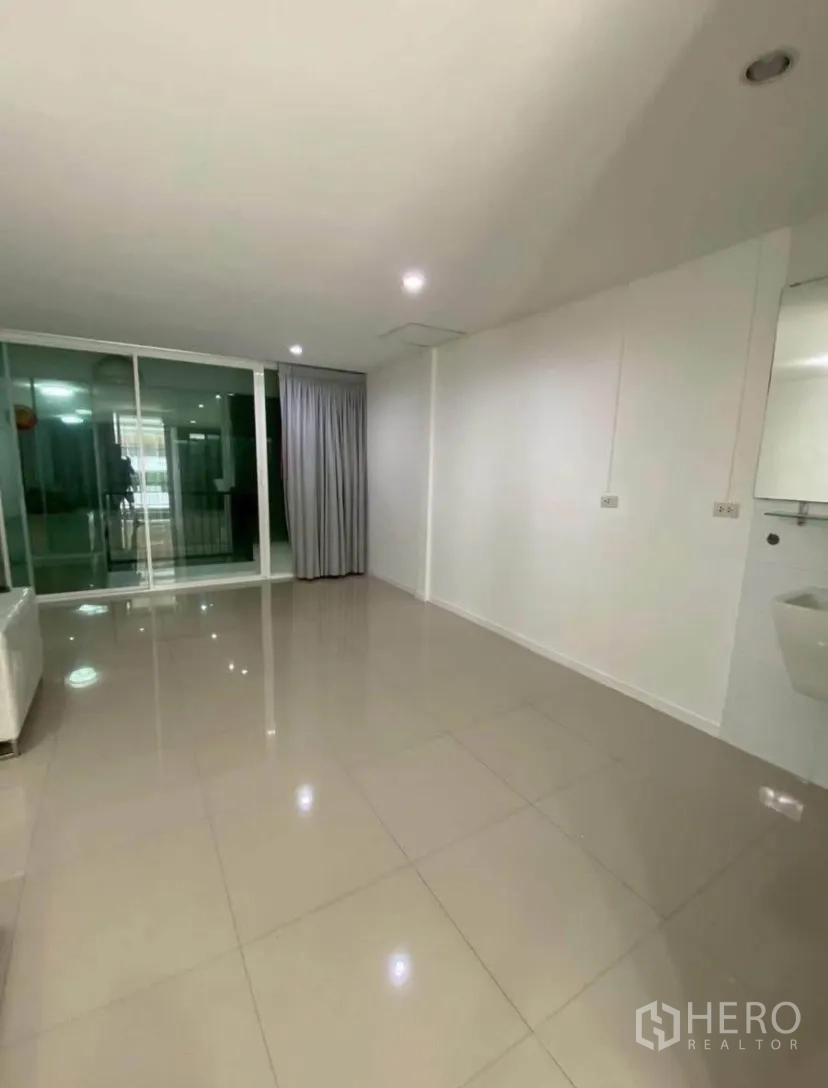 Townhouse for rent in Phra Khanong, Bangkok - Upper-floor room with sliding glass doors and curtains opening to the balcony.