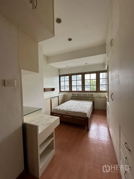 Townhouse for rent in Khlong Toei, Bangkok - Cozy secondary bedroom with built-in storage, study desk and wide windows.