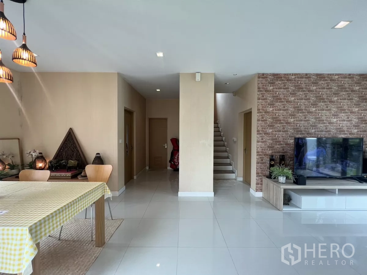 Detached House for rent in Bang Kapi, Bangkok - Open ground floor showing dining set, TV wall, and staircase.