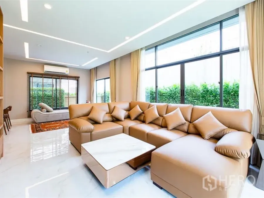 Detached House for rent or sale in Prawet, Bangkok - Open-plan lounge featuring an L-shaped sofa, marble floors and full-height windows.