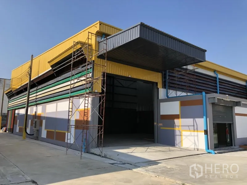 Factory for rent in Khlong Luang, Pathum Thani - Corner angle of a factory bay with open entrance and scaffolding during final works.