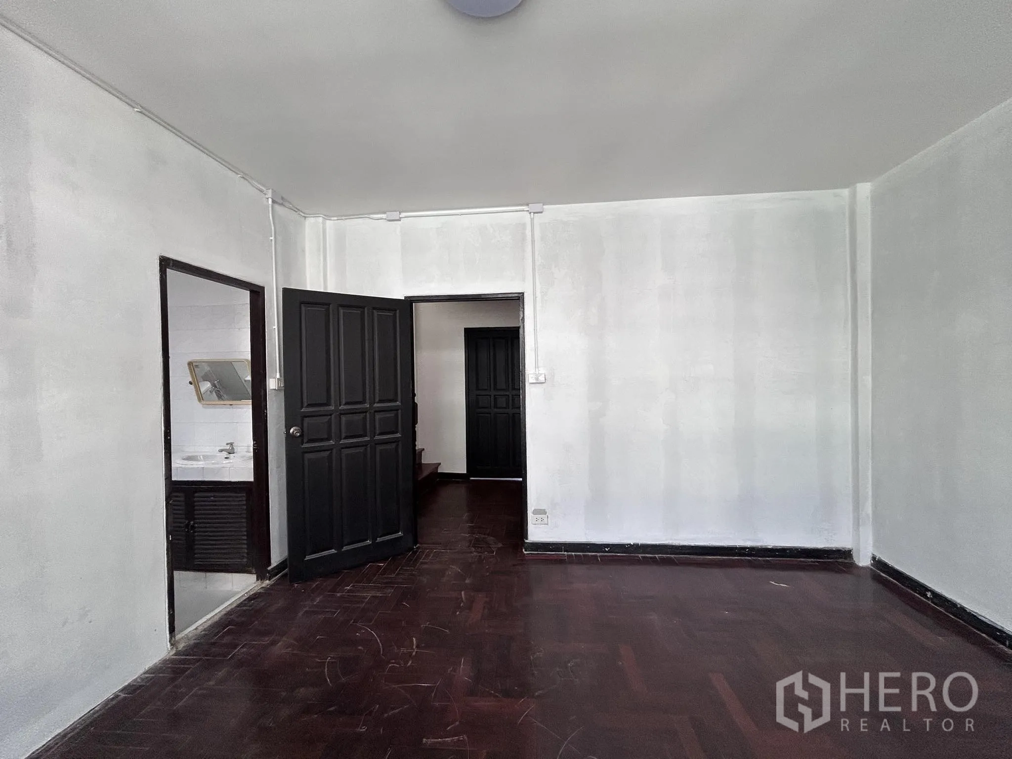 Home Office for rent or sale in Watthana, Bangkok - Spacious room with dark wood floor and door to bathroom.