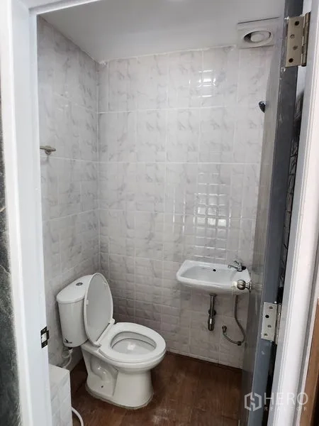 Warehouse for rent in Lam Luk Ka, Pathum Thani - Compact white-tiled bathroom with toilet and wall-mounted sink.