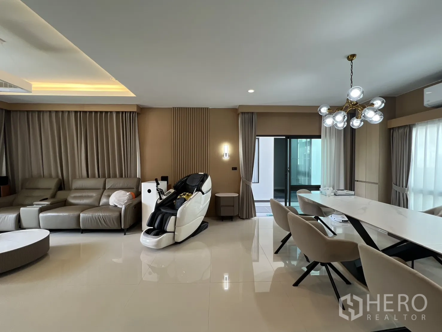 Detached House for rent or sale in Mueang Pathum Thani, Pathum Thani - Lounge and dining zone with chandelier, leather sofa and access to the terrace.