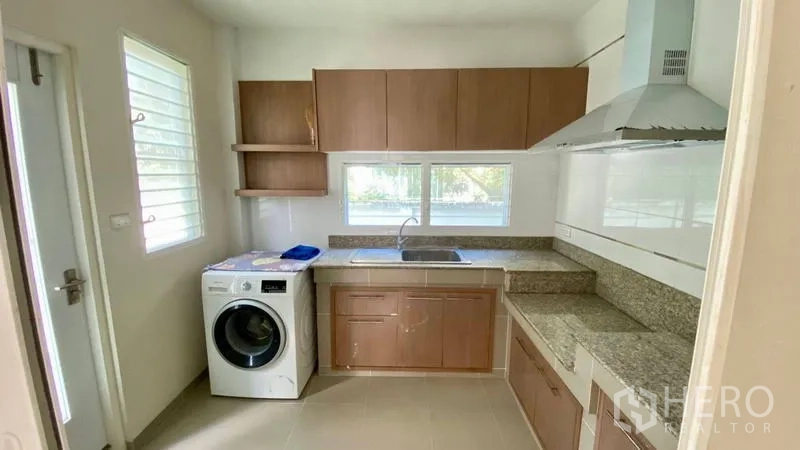Detached House for rent in Bang Kapi, Bangkok - Closed kitchen with granite counters, cabinets and washing machine.