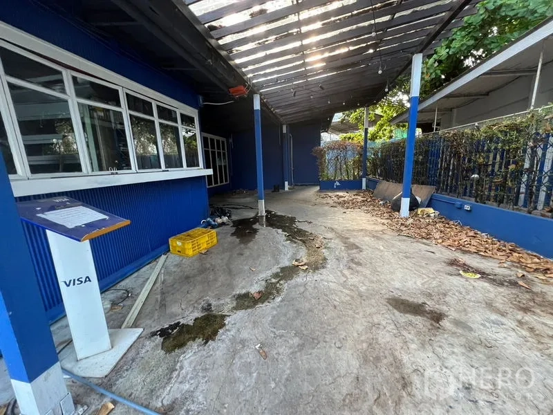 Retail Space for rent in Watthana, Bangkok - Covered outdoor walkway beside blue walls with a service counter and concrete floor.