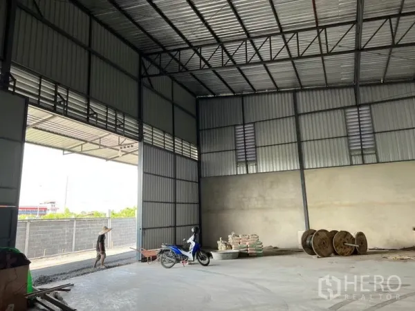 Warehouse for rent in Lam Luk Ka, Pathum Thani - Tall roller shutter entrance opening to a covered loading area, truck-friendly concrete floor.