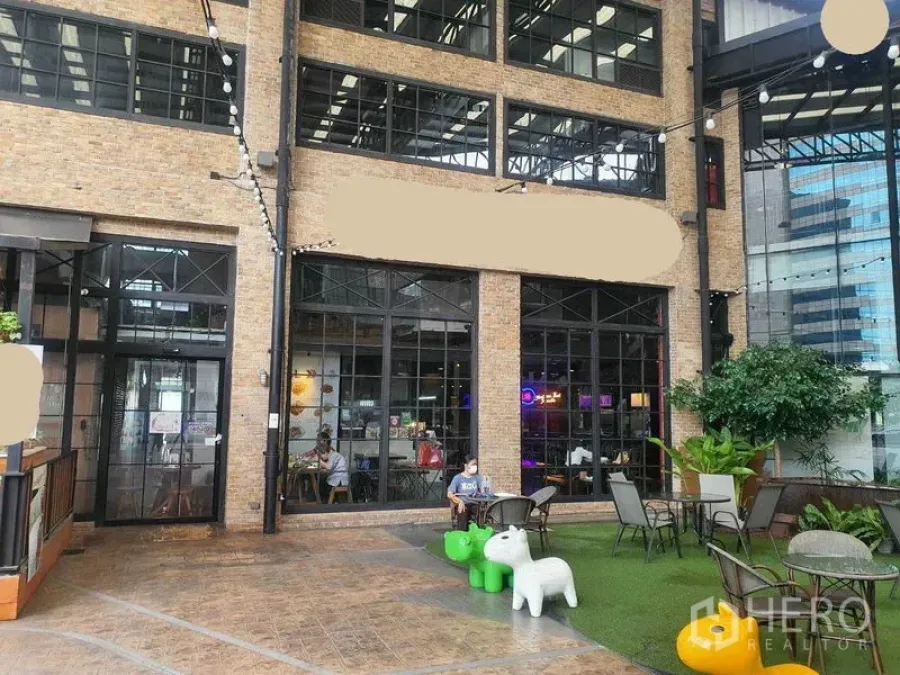 Retail Space for rent in Khlong Toei, Bangkok - Brick façade storefront with tall black-framed windows, outdoor patio seating, string lights and greenery in the Phrom Phong area.