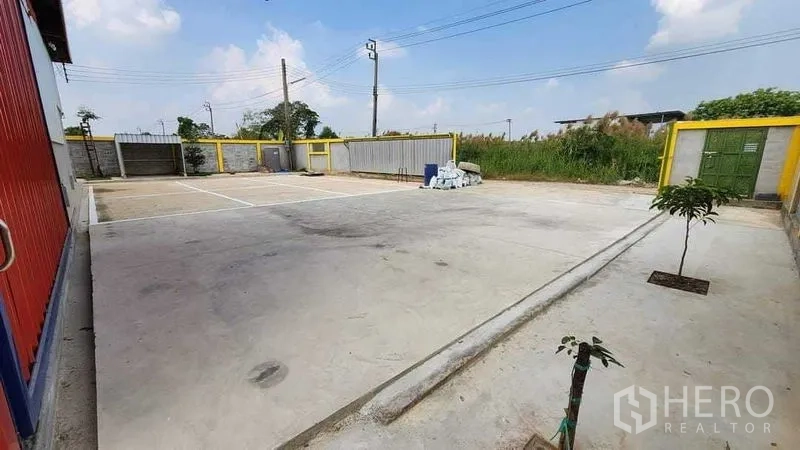 Warehouse for rent in Nong Chok, Bangkok - Large concrete yard with marked parking bays and wide vehicle access in front of the warehouse.